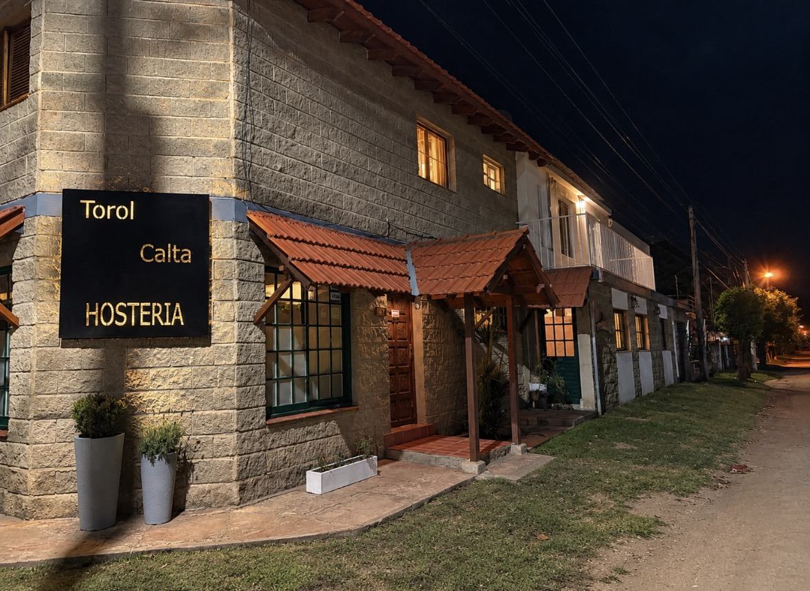 Frente de la hostería Torol Calta de noche, con el cartel